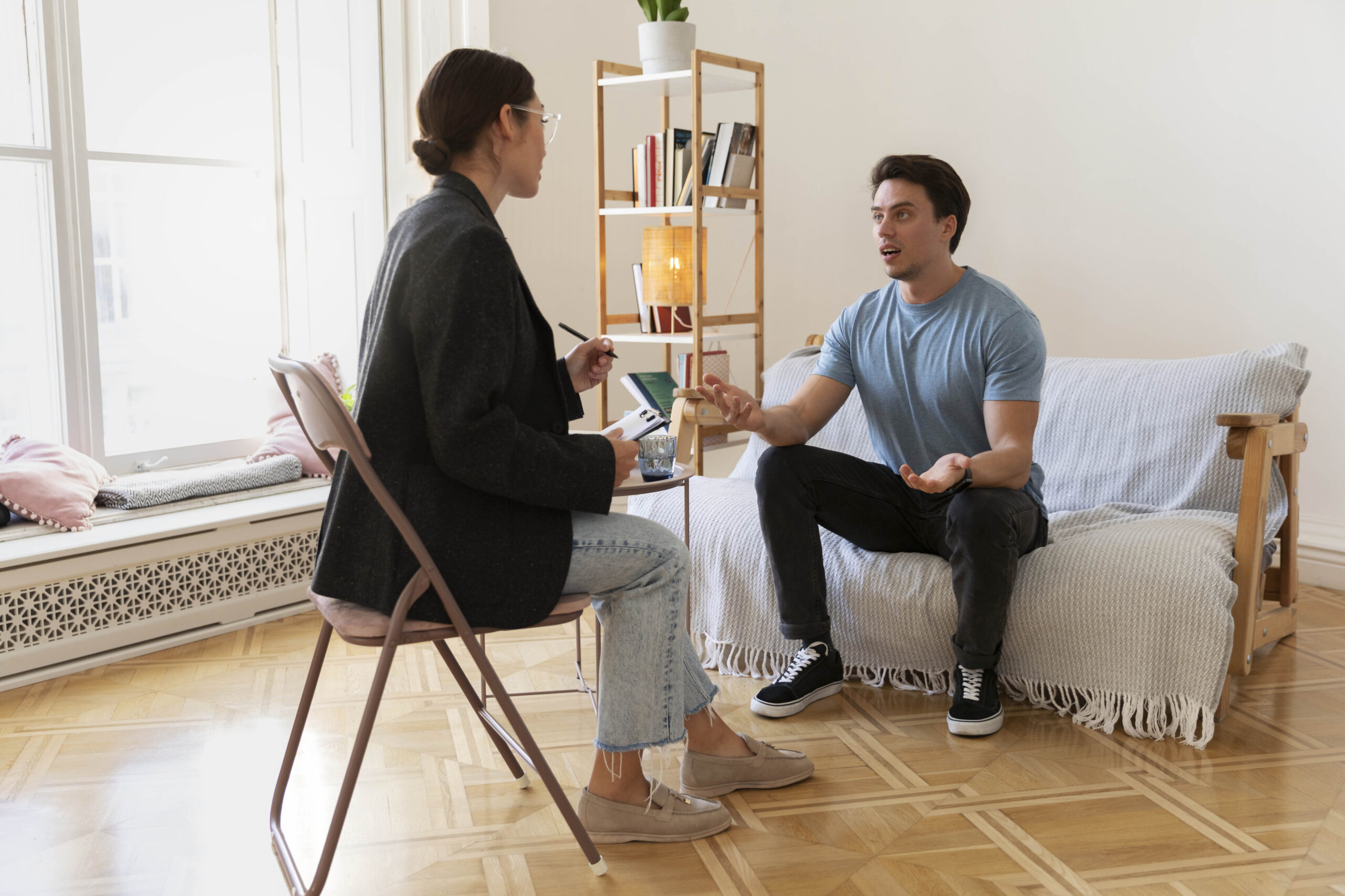 Therapist talking with an adult client in a bright therapy room